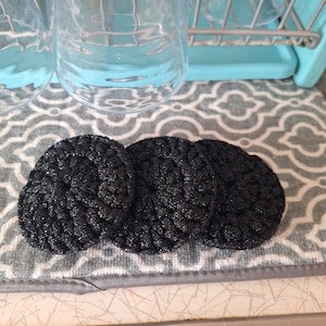 May include: Three black, round, textured, crocheted hair scrunchies.