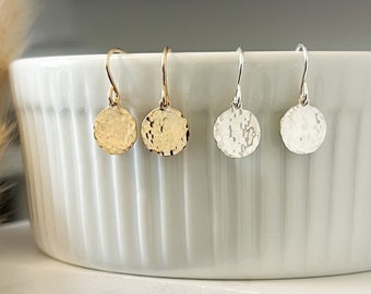 Platte, gehamerde oorbellen met tekststructuur in de vorm van een schijf, verkrijgbaar in verguld of sterling zilver. Ronde oorbellen, lichtgewicht en minimalistisch, perfect voor elke dag.