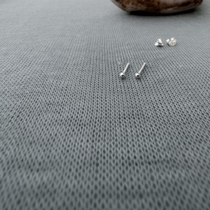May include: A set of four silver stud earrings. The earrings are small and round, with a smooth finish.