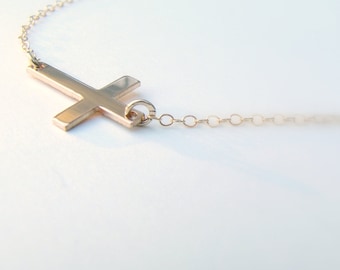May include: A gold cross pendant necklace with a delicate chain.
