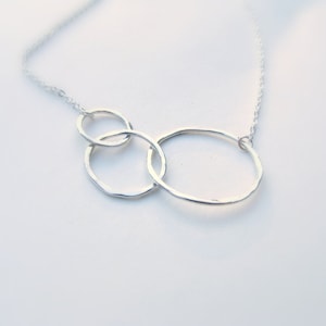 May include: A silver necklace with three interconnected circles, each with a hammered texture.