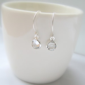 May include: A pair of silver dangle earrings with clear round crystal stones.
