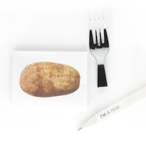May include: A white sticky note with a brown potato illustration and the text "Raw potato - cook before eating". A white pen with the text "I'm a pen!" and a silver fork are also pictured.