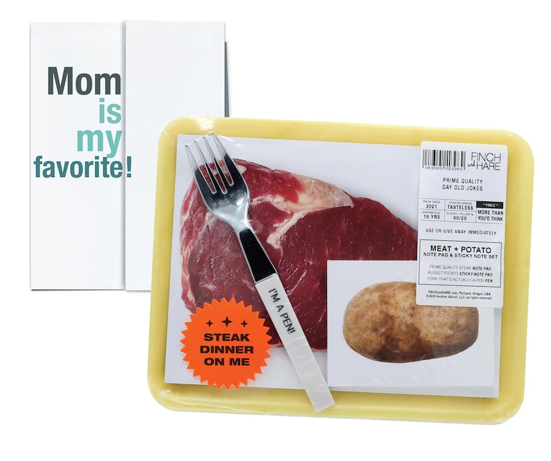 May include: A yellow styrofoam tray with a steak, potato, and a fork. The tray has a sticker that says "Steak Dinner On Me" and another sticker that says "I'm a Pen!" The tray also has a label that says "Prime Quality Day Old Jokes".