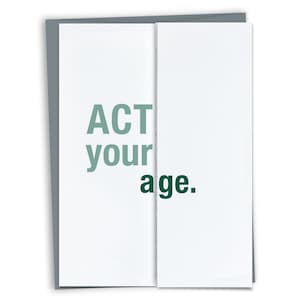 May include: A white greeting card with the text "ACT your age." The words are in a mix of green and dark green. The card is folded in the middle and has a gray border.