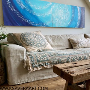 a cozy living room with a large window overlooking a cityscape. The room is furnished with a beige sofa, a wooden coffee table, and a large abstract painting on the wall. The room is decorated with various plants and books, creating a warm and inviting atmosphere.