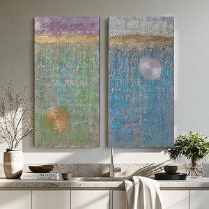 a modern, well-lit kitchen with white cabinets, a large window, and a colorful abstract painting on the wall.
