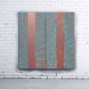 a large, abstract painting with vertical stripes in shades of blue and red, displayed on a white brick wall.