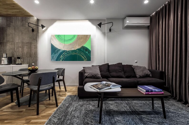 a modern living room with a black sofa, a wooden coffee table, and a dining table with chairs. The room has a minimalist and contemporary design, with a large abstract painting on the wall and a window with curtains.