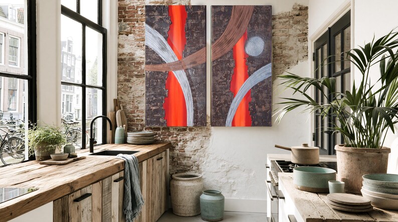 a modern kitchen with a large abstract painting hanging on the wall above a wooden counter. The kitchen features a rustic wooden counter, a sink, and various kitchen accessories such as bowls, cups, and a potted plant. The overall design has a mix of natural and industrial elements, creating a visually appealing and functional space.