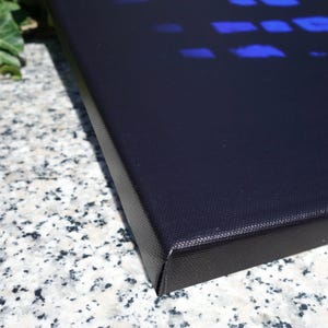 a close-up view of a black, textured surface, possibly a piece of artwork or a canvas, with a blue pattern or design on it.
