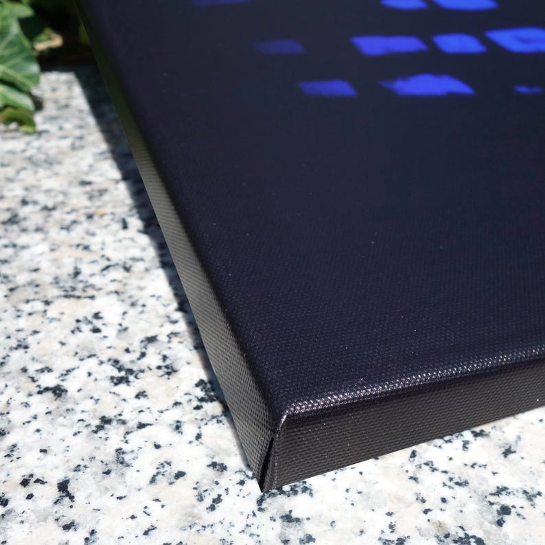 a close-up view of a black, textured surface, possibly a piece of artwork or a canvas, with a blue pattern or design on it.