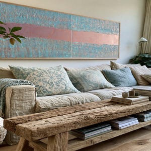 a cozy living room with a large window, a comfortable sofa with pillows, a wooden coffee table, and various decorative elements such as a potted plant, a vase, and a painting on the wall.