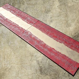 a red and white striped object, possibly a sign or a piece of art, placed on a textured surface.