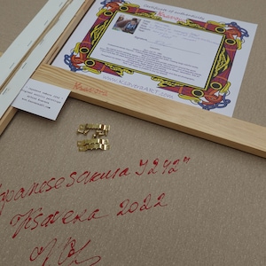 a Japanese calligraphy piece with a certificate of authenticity, a wooden frame, and some gold hardware.