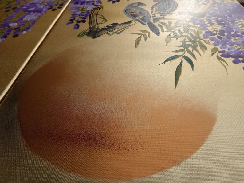 a close-up view of a painting with a large circular shape in the center, surrounded by various elements such as birds, leaves, and flowers. The painting appears to be a close-up of a larger artwork, possibly a collage or a section of a larger painting.