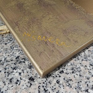 a close-up view of a textured surface, possibly a wooden board or a piece of paper, with the name "Miguel" written on it in cursive.