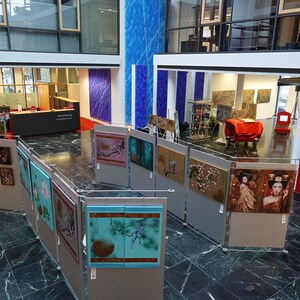 Puede incluir: Una galer&iacute;a de arte exhibe una colecci&oacute;n de pinturas enmarcadas de inspiraci&oacute;n asi&aacute;tica. Las obras presentan temas florales y de geishas, con una variedad de colores y estilos. La galer&iacute;a est&aacute; ubicada en un edificio moderno con suelo de m&aacute;rmol.