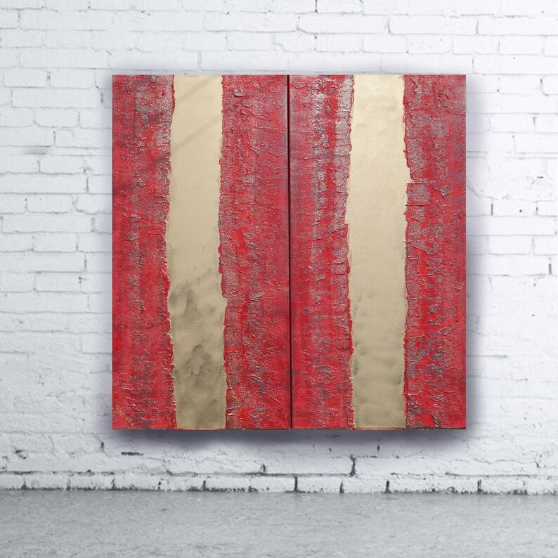 a striking red and gold abstract artwork displayed on a white brick wall.