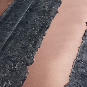 a close-up view of a textured surface with a striped pattern, featuring a mix of black and pink colors.