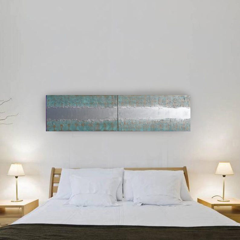 a modern bedroom with a large bed, white bedding, and two nightstands with lamps. Above the bed is a large, rectangular artwork featuring a metallic, textured design in shades of blue and silver.
