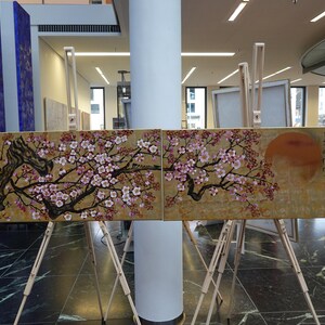 two large paintings displayed on easels in an indoor setting.