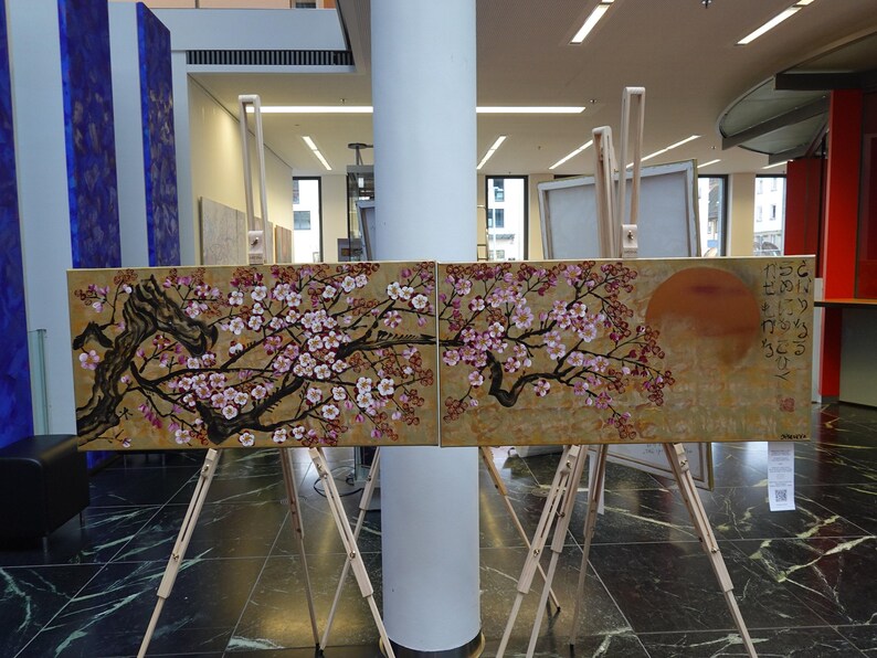two large paintings displayed on easels in an indoor setting.