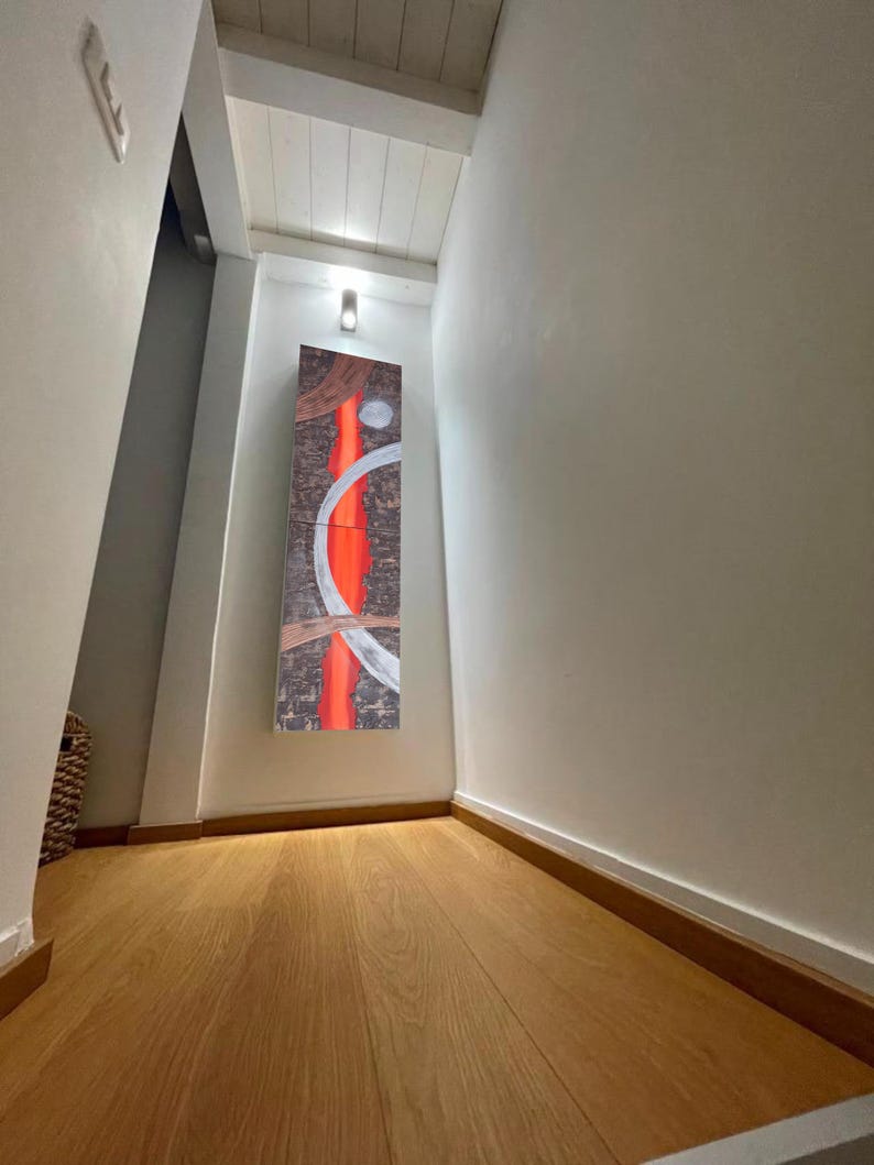 a hallway with a wooden floor and white walls. There is a large abstract painting hanging on the wall, which appears to be the focal point of the hallway.