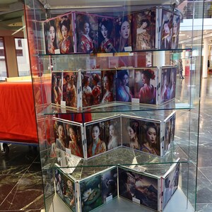 Puede incluir: Una vitrina de cristal que muestra m&uacute;ltiples im&aacute;genes de geishas con vestimenta tradicional. Las im&aacute;genes presentan mujeres con peinados elaborados y kimonos coloridos. La exhibici&oacute;n est&aacute; en un &aacute;rea bien iluminada con suelo de m&aacute;rmol.