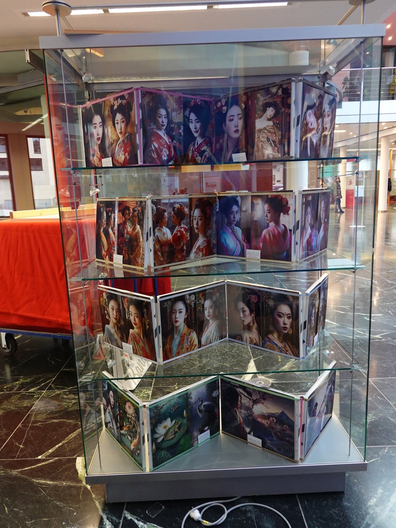 Puede incluir: Una vitrina de cristal que muestra m&uacute;ltiples im&aacute;genes de geishas con vestimenta tradicional. Las im&aacute;genes presentan mujeres con peinados elaborados y kimonos coloridos. La exhibici&oacute;n est&aacute; en un &aacute;rea bien iluminada con suelo de m&aacute;rmol.