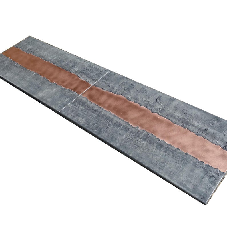a long, rectangular surface with a metallic, copper-colored line running through it, creating a striking contrast against the gray background.