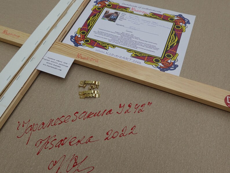a wooden frame with a certificate of authenticity, a piece of paper with Japanese calligraphy, and some gold hardware.