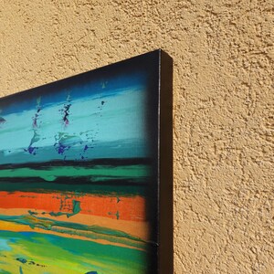 The image is a vibrant abstract painting with bold colors and brushstrokes, displayed on a wall.