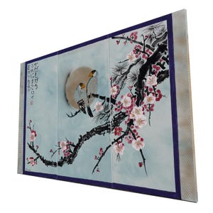 A large, colorful painting depicting two birds perched on a branch with pink flowers. The background is a light blue color, and the birds are depicted in a stylized, traditional Japanese-inspired manner.