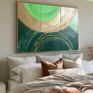 a large, colorful abstract painting hanging on a wall above a bed with white pillows and a brown throw pillow.
