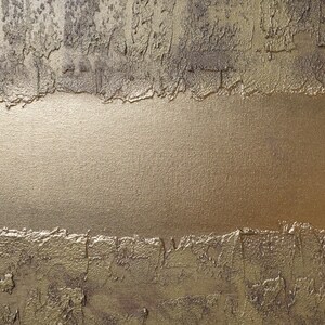 The image is a close-up of a textured surface with a golden or metallic sheen, featuring a rough, uneven texture with visible cracks and crevices.