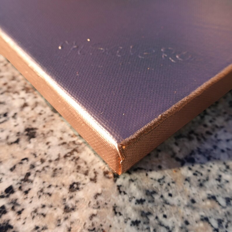 a close-up view of a textured surface, possibly a piece of fabric or paper, with a metallic or textured finish.