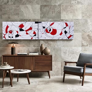 a modern living room with a large abstract painting on the wall, a wooden sideboard with a lamp and decorative items, a gray armchair, and a round coffee table.