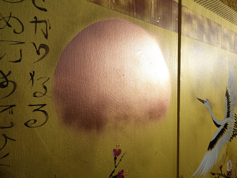 The image is a close-up of a painting featuring a large, round shape resembling a sun or moon, with a bird in flight in the background.
