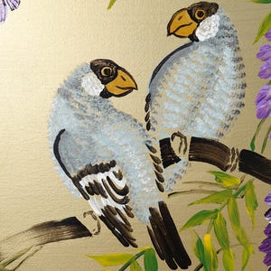two birds perched on a branch, surrounded by purple flowers and green leaves.