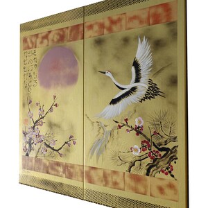 The image is a large painting featuring a crane in flight, surrounded by cherry blossoms and a sun. The painting is set against a yellow background with a decorative border.