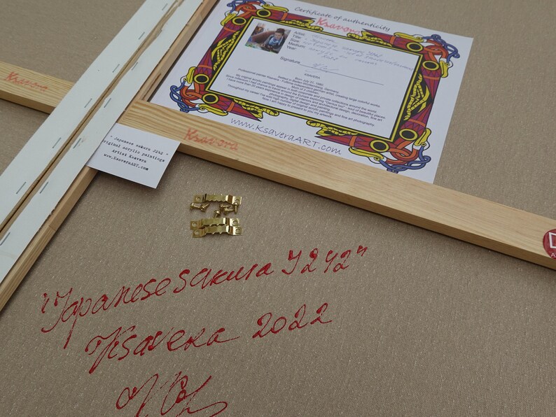 a wooden frame with a certificate of authenticity, a piece of paper with Japanese calligraphy, and some gold hardware.