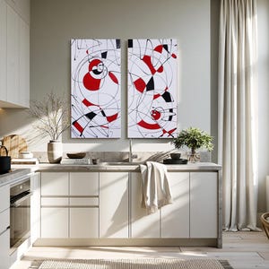 a modern kitchen with white cabinets, a large abstract painting on the wall, and a dining table with chairs.