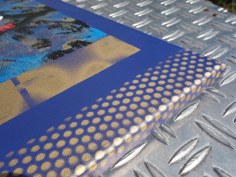 a close-up view of a blue and gold patterned surface, possibly a canvas or a piece of fabric, with a metallic texture.
