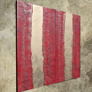 a large, abstract painting with bold red and white vertical stripes. The painting is displayed on a wall, creating a striking visual contrast against the textured background.