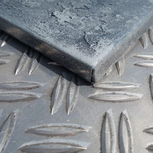 a close-up view of a metal surface with a textured, metallic appearance. The surface appears to be a combination of metal and glass, with a metallic sheen and a textured, metallic pattern. The image does not contain any text or other discernible objects or actions.