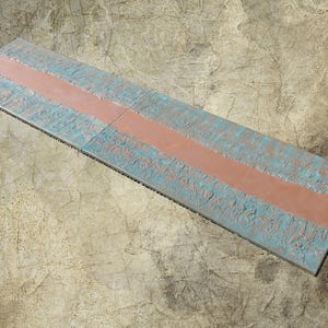 a long, narrow, and weathered surface with a horizontal line running through it. The surface appears to be made of concrete or a similar material, with a faded and worn appearance.