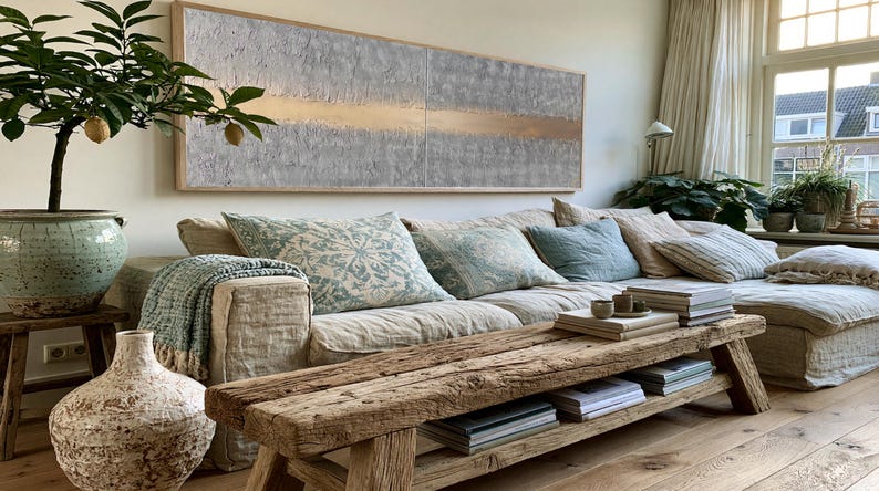 a cozy living room with a large window, a comfortable sofa with patterned pillows, a wooden coffee table, and various decorative elements such as a potted plant, a vase, and a painting on the wall.