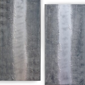 two abstract paintings with a textured, metallic appearance. The paintings are vertically oriented, with a vertical line running through them, creating a sense of depth and movement.