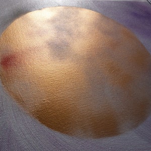 May include: A close-up of a gold-colored circle painted on a canvas background. The circle has a textured surface and appears to be a depiction of the moon.